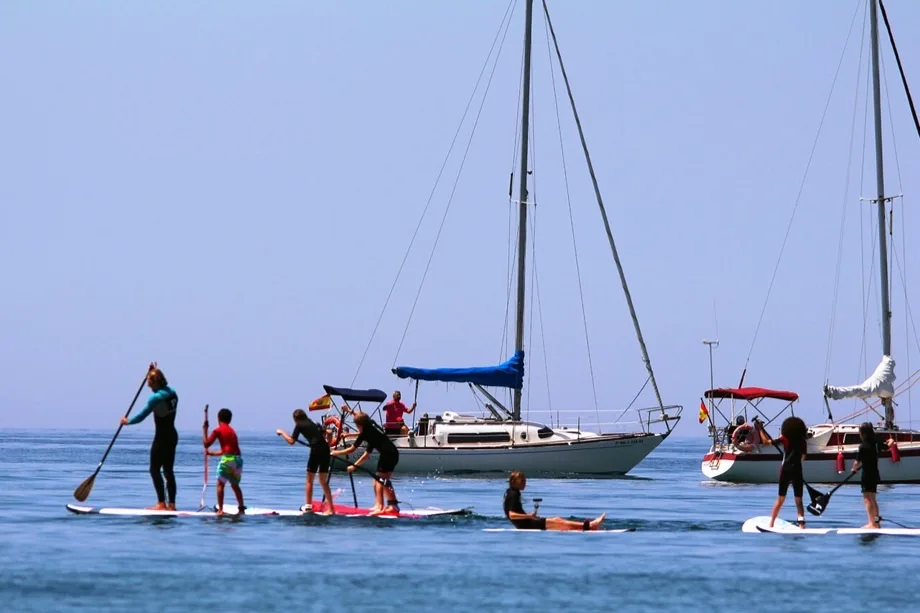 Grupo de paddle surf junto a un velero fondeado en Almerimar